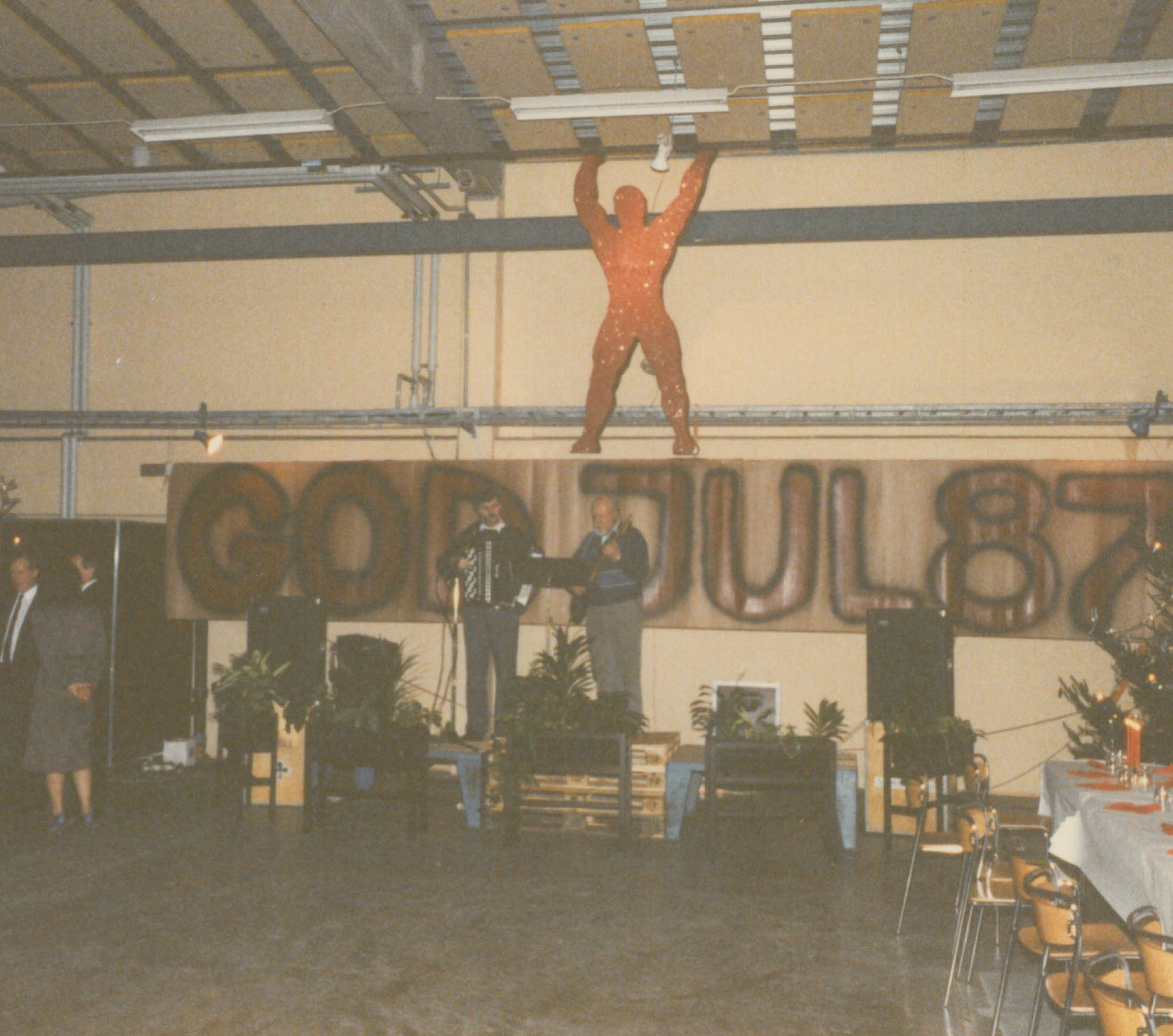 Christmas celebration, 1987 — band on stage, banner reading GOD JUL 87, the red 'Viking' figure suspended overhead